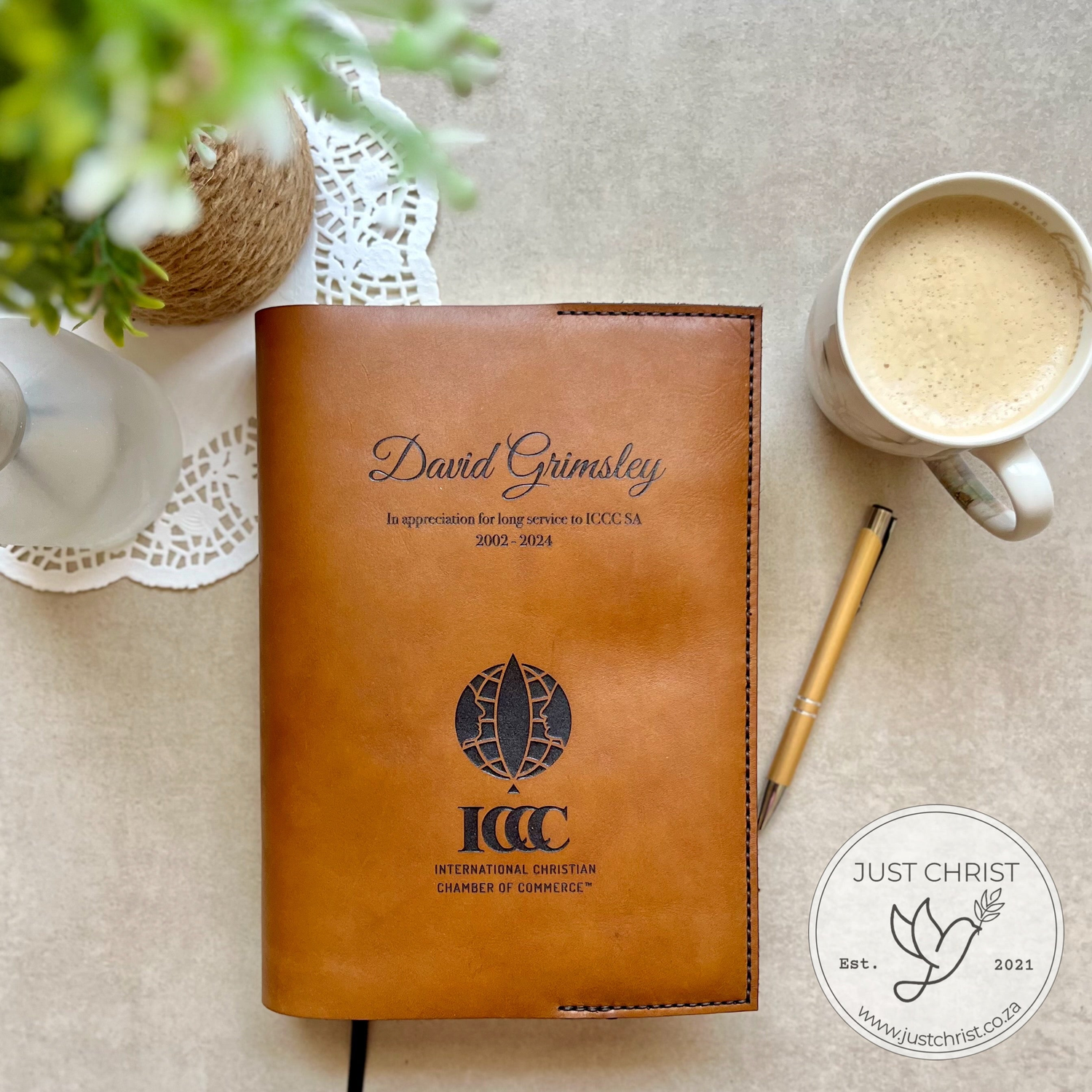 A Bible slip-on cover, showing only the front side. A bunch of lilies and a name is engraved on the front cover. The cover is made out of beige real leather and stitched by the hand.